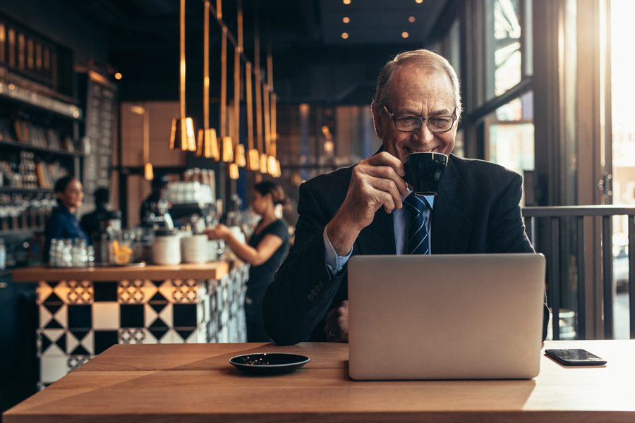 Business Insurance - Man Drinking a Coffee in a Coffee Shop Waiting for a Video Call